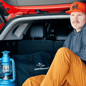 White Duck Outdoors Hoplite Canvas Parachute Bag black in car next to man