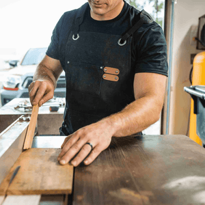 White Duck Outdoors Black Work Apron with man doing woodwork