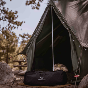 White Duck Outdoors Hoplite Canvas Duffel Bag black in front of tent