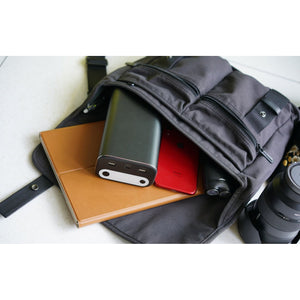 Photo of the Bluetti - AC10 99Wh/26756mAh Portable Power Station with a phone and a notebook in a bag.