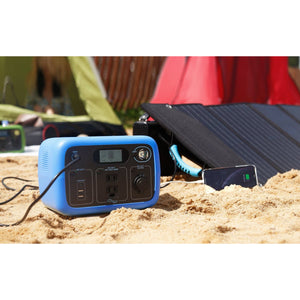 Photo of Bluetti - AC30 300Wh/300W Portable Power Station in color blue charged in a solar panel placed in a sand.