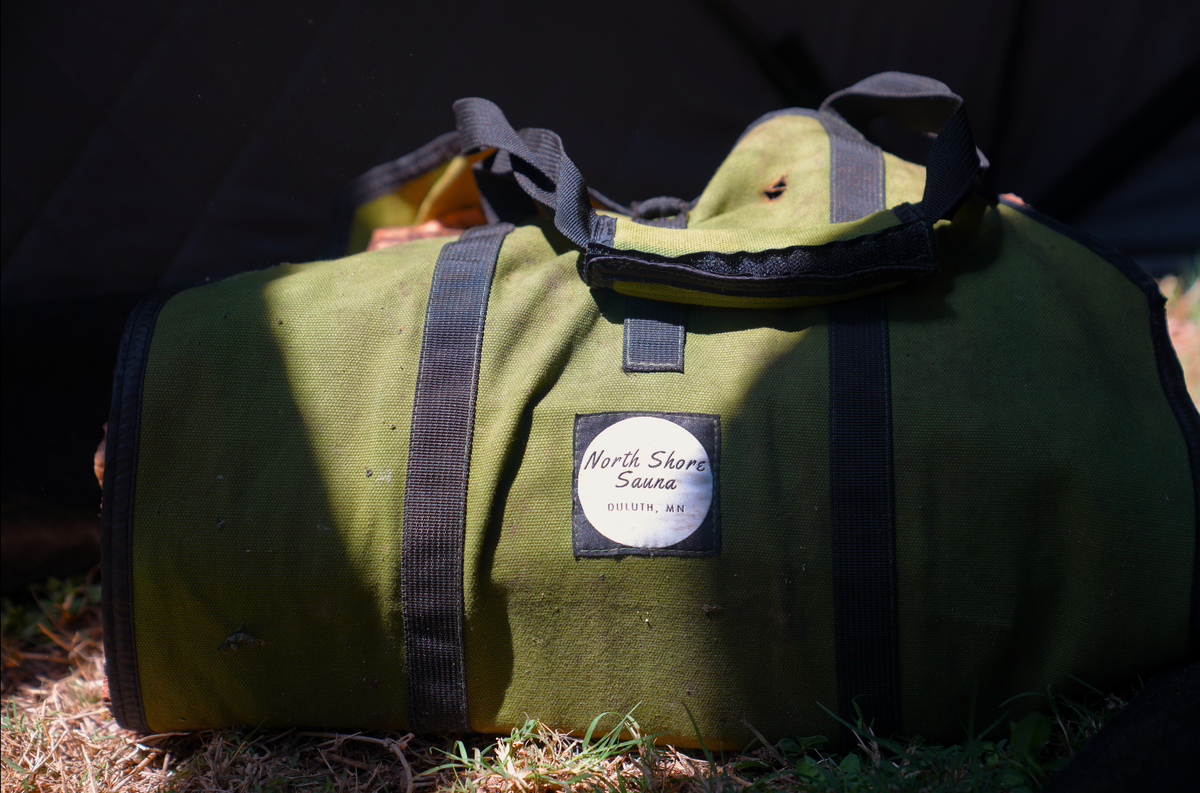 Picture of North Shore Sauna Firewood Carrying Bag on Grass with logo showing 