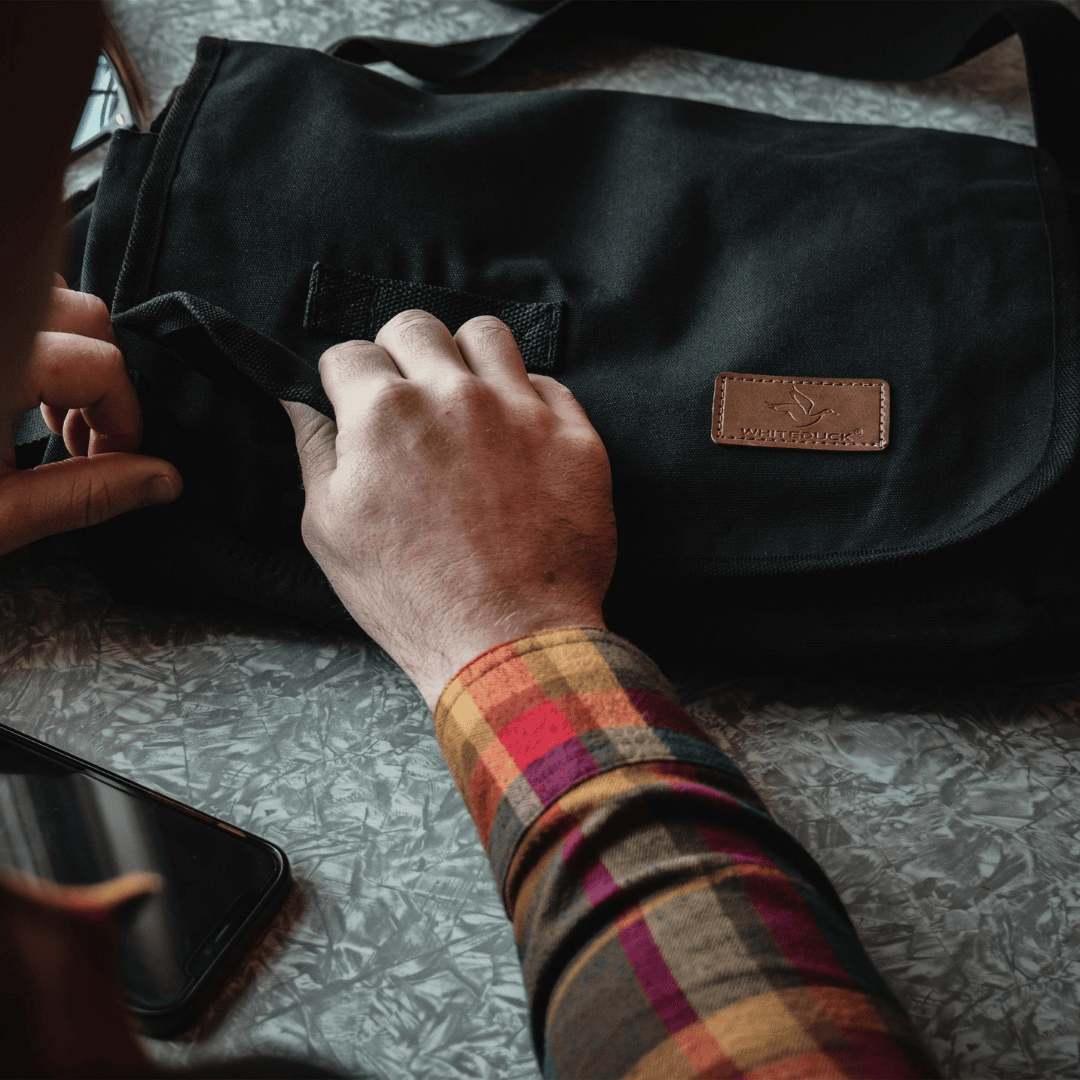 White Duck Outdoors Filios Messenger Bag black with man&#39;s hand
