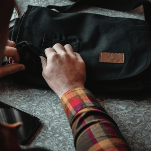 White Duck Outdoors Filios Messenger Bag black with man's hand