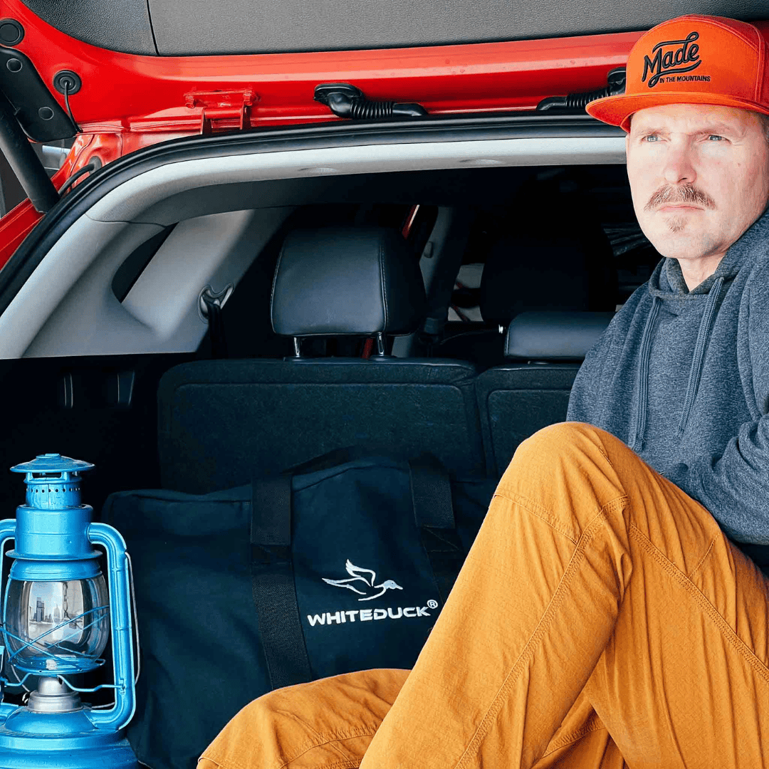 White Duck Outdoors Hoplite Canvas Parachute Bag black in car next to man