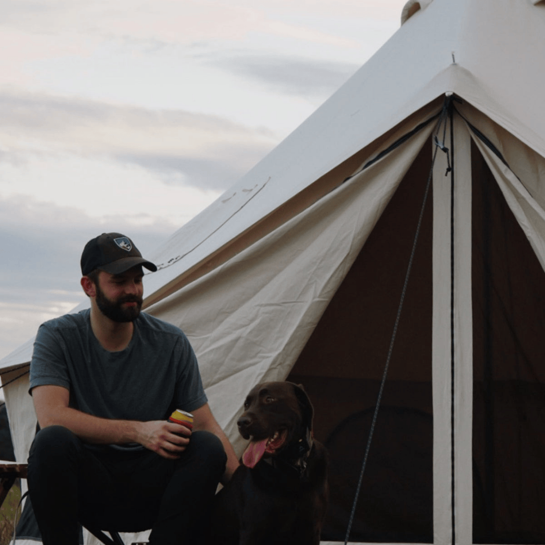White Duck Outdoors Avalon Bell Tent with man and dog sitting in front