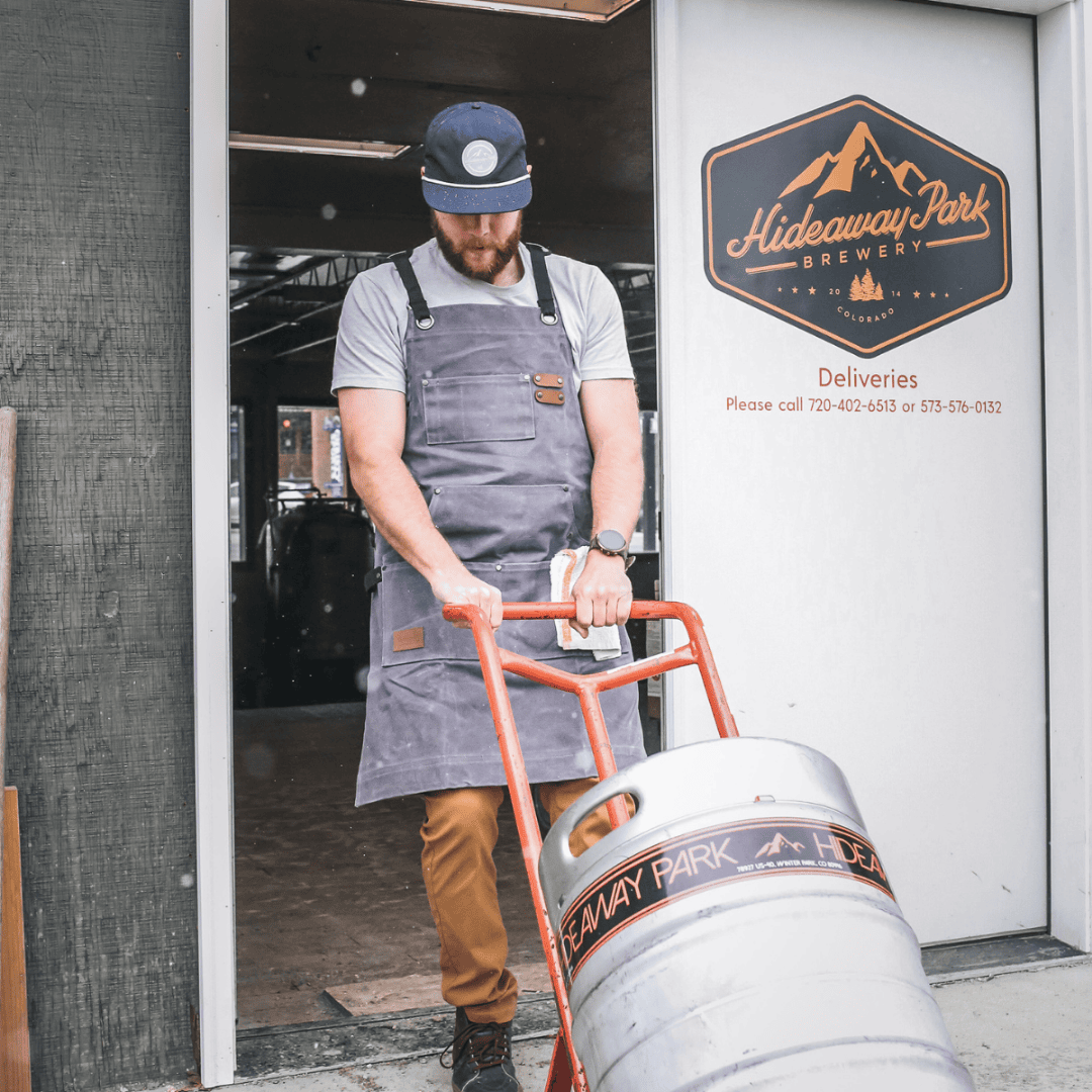 White Duck Outdoors Charcoal Work Apron with man hauling a barrel