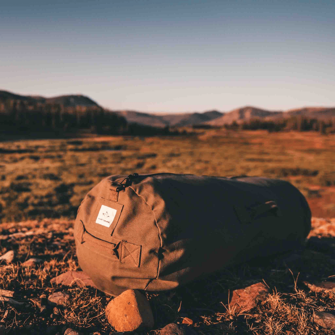 White Duck Outdoors Hoplite Canvas Duffel Bag brown on grass