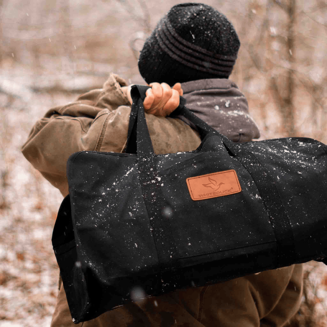 White Duck Outdoors Tote Canvas Log Carrier Bag black with man carrying it over his shoulder