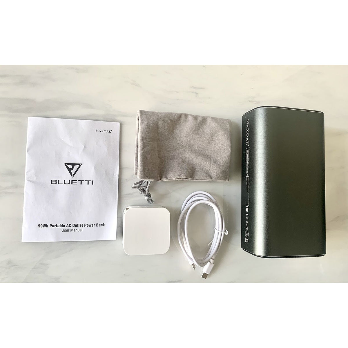 Photo of the Bluetti - AC10 99Wh/26756mAh Portable Power Station with the charger and the manual.