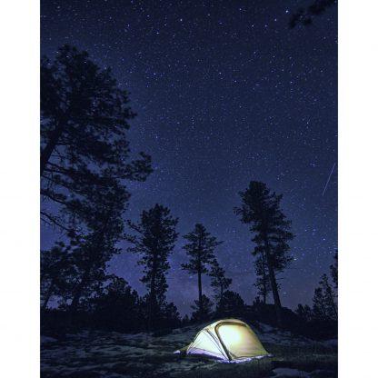 Photo of the Catoma Wolverine tent outdoor at night in a forest with lights inside it.