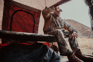 Picture of a man sitting in a Disc-O-Bed Cam-O-Bunk XL with Mossy Oak including Organizers.